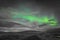 Aurora Borealis in Iceland northern lights bright beams rising green over hiking path and clouds in black white and accent color