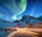 Aurora borealis on the Lofoten islands, Norway. Road traffic and blur car light. Green northern lights above mountains. Night sky