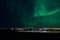 Aurora borealis over tromso city island, fjord and snowy mountain