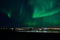 Aurora borealis over tromso city island, fjord and snowy mountain