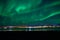 Aurora borealis over tromso city island, fjord and snowy mountain