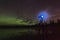 Aurora reflecting of a lake, city lights lighting up clouds - Camera in forground