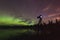Aurora reflecting of a lake, city lights lighting up clouds - Camera in forground