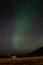 Aurora in the sky among the farmland with grassland and small house in Iceland