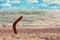 Australian Boomerang on sandy coastline against sea wave and sky