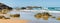 Australian coast with volcanic rocks at the shore, view from the beach to the horizon with blue water with waves