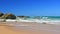 Australian coast with volcanic rocks at the shore, view from the beach to the horizon with blue water with waves on a summer