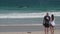 Australian couple sanding on a beach looking at a large female Humpback whale