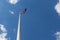 Australian flag on a tall flagpole waving in the blue sky with copy space,