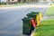 Australian garbage wheelie bins with colourful lids for recycling and general household waste lined up on the street kerbside