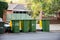 Australian garbage wheelie bins with colourful lids for recycling waste lined up on the street kerbside for council collection