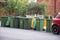 Australian garbage wheelie bins with colourful lids for recycling waste lined up on the street kerbside for council collection