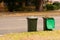 Australian garbage wheelie bins with green lids for green garden waste lined up on the street for council waste collection