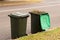 Australian garbage wheelie bins with green lids for green garden waste lined up on the street for council waste collection