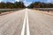 Australian sealed tarmac road leading into the bush tree line