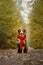 Australian Shepherd red tricolor wrapped up in warm knitted red scarf and sits on trail in woods in fall. Beautiful fluffy