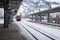 Austria / Zell am See - February 06 2013: Red passenger high-speed train pulls up to stop at deserted snow-covered railway station