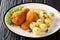 Austrian deep-fried breaded chicken served with lemon and new potatoes close-up on a plate. horizontal