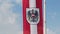 Austrian flag with emblem waving in wind, blue sky background