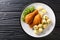 Austrian Fried Chicken Backhendl served with lemon and new potatoes close up in the plate. Horizontal top view