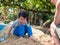 Authentic asian child boy playing sand on foot with father outdoor in nature with smiling face.