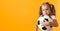 Authentic cute smiling preschool little girl with classic black and white soccer ball look at camera on yellow
