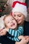 Authentic family christmas portrait in front of xmas tree. Smiling mother and daughter at christmas.