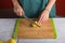 Authentic female hands cutting potatoes on wooden cutting board on gray kitchen table