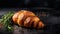 Authentic French Croissant With Rosemary Leaf On Black Countertop