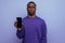 authentic handsome young african man in blue sweater holding smartphone vertically with mockup for advertisement on blue