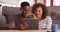 Authentic millennial black couple sits on floor watching a video on their tablet