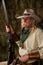 Authentic old west cowboy with shotgun, hat and bandanna in stable portrait