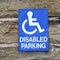 Authentic painted blue and white disabled parking sign on rustic stone wall