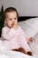Authentic portrait cute caucasian little infant chubby baby girl or boy in pink sleepy upon waking looking at camera in