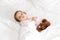 Authentic portrait cute caucasian little infant chubby baby girl or boy in pink sleepy upon waking with teddy bear