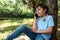 Authentic portrait handsome teenage schoolboy talking on smart mobile phone while chilling out in the park after school.