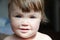 Authentic portrait of smiling baby girl. Little child face closeup in natural light at home. Caucasian kid