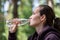 Authentic portrait of woman in purple hoodie drinking water in fresh air