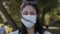 Authentic portrait of a young woman wearing a medical mask in a park.