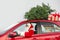 Authentic Santa Claus driving red car with gift boxes