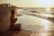 Authentic woman in swimsuit doing yoga padmasana on the beach in the morning. Real unretouched shape girl silhouette in