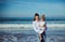 Authentic young woman talking with her daughter while carrying her, walking together on the beach