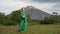 Authenticity blonde woman in green leather coat walking in forest against background of mountain