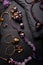 author collection jewelry with lilac gemstones, crystals and pearls demonstrated at black stones background with lilac flowers.