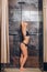 Autiful woman standing at the shower. In a black bathing suit