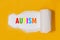 AUTISM, word written multicolored letters under torn yellow  paper. AUTISM, concept Image