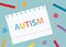 Autism written in notebook with colorful pencils and puzzle pieces