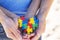 Autistic kid hands supported by mother holding multicolored puzzle heart. World autism awareness day concept