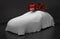 Auto concept of a new covered sports car topped with a red ribbon as a gift