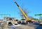 Auto crane lifling truck with concrete slabs on construction site Construction worker navigating with concrete slab lifted by